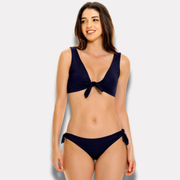 Mujer posando con bikini azul marino multiuso de top anudado y calzón ajustable.