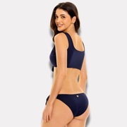 Modelo mostrando bikini azul marino con top estilo deportivo y amarre trasero.