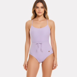 Mujer de frente con traje de baño entero lila, tirantes finos y lazo en la cintura.