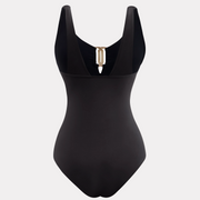 Traje de baño entero negro para mujer con control de abdomen, detalle metálico dorado en escote – vista posterior.
