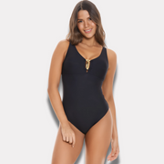Modelo sonriendo con traje de baño entero negro, escote en V y adorno metálico dorado – vista frontal.
